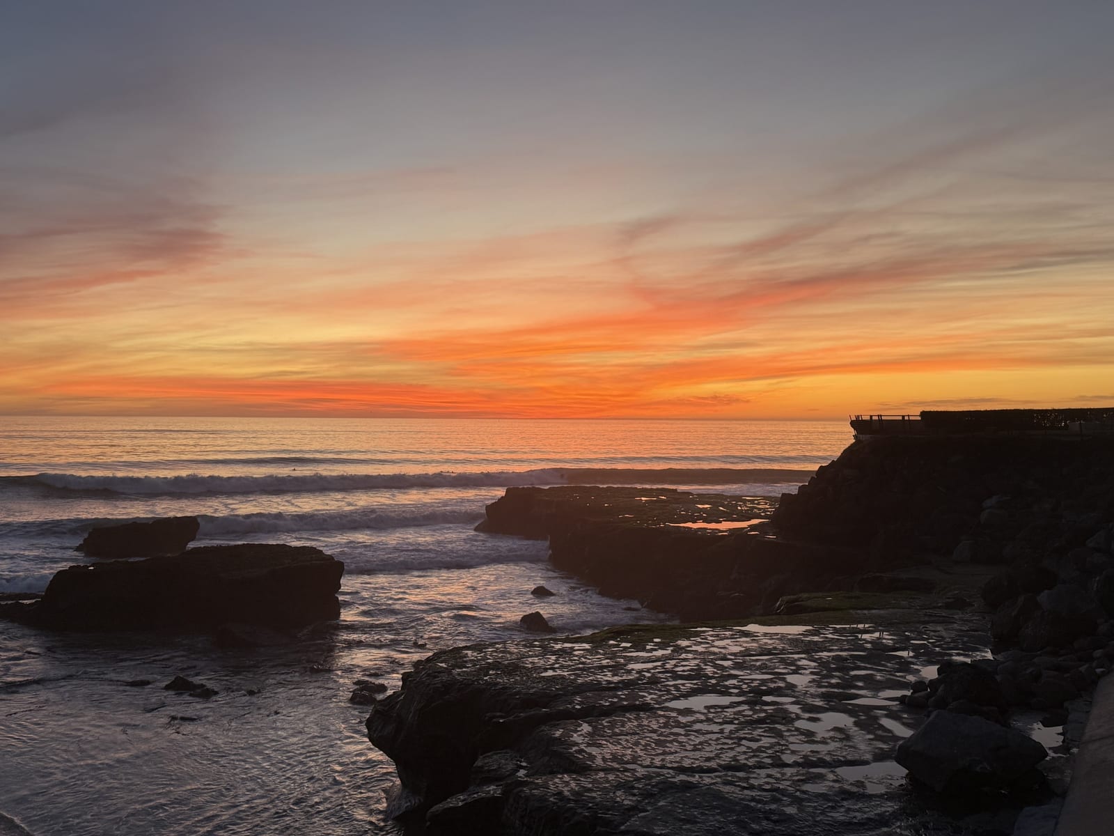 Orange and pink sunset over the tide-pool rock shelves along West Cliff Drive in Santa Cruz