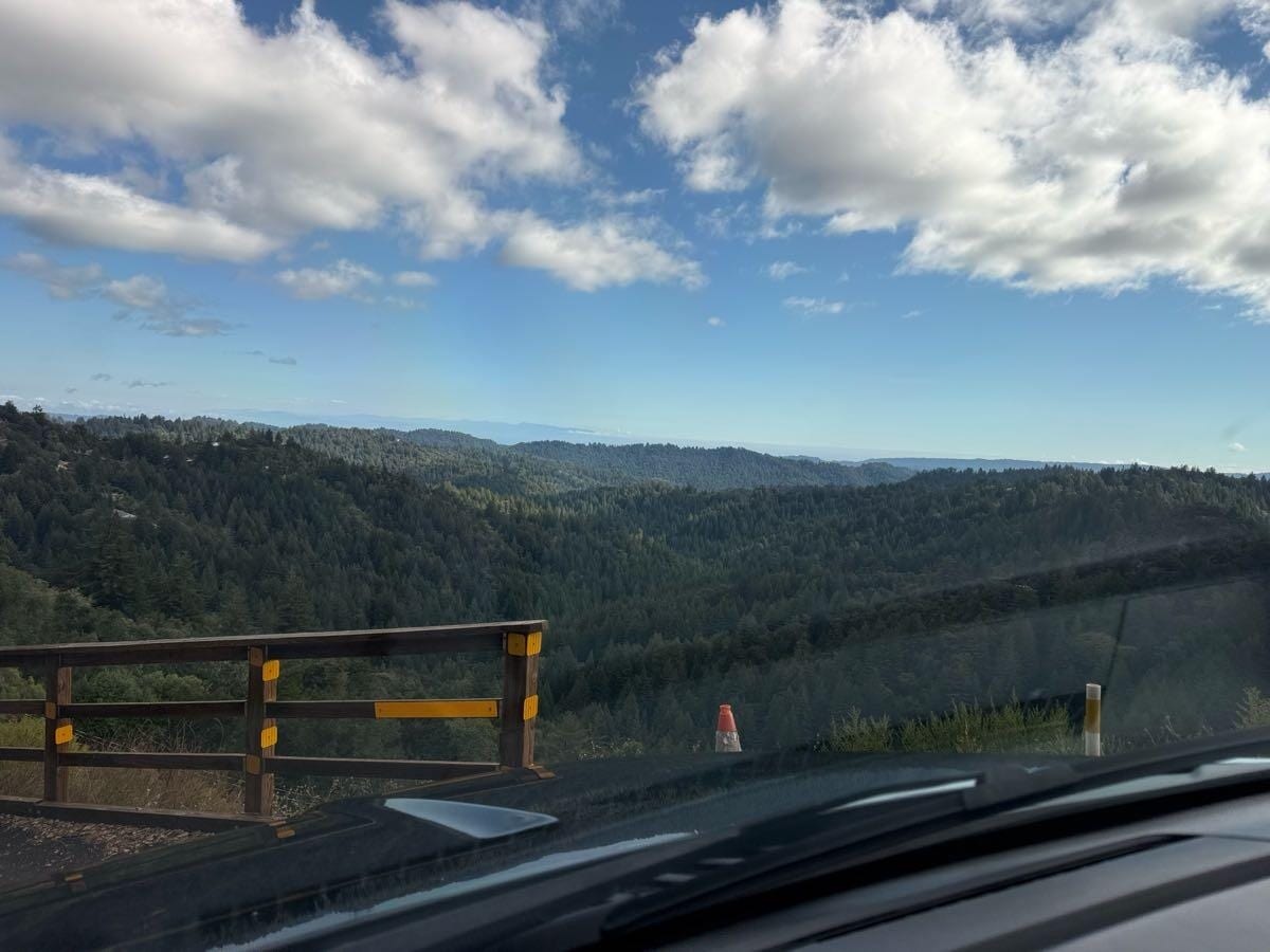 View over forested ridges from a mountaintop pullout in Los Gatos, seen over the SUV hood